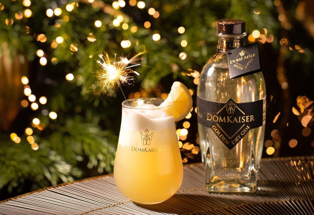 Golden Dry Gin Flasche mit dekoriertem Glas auf Tisch