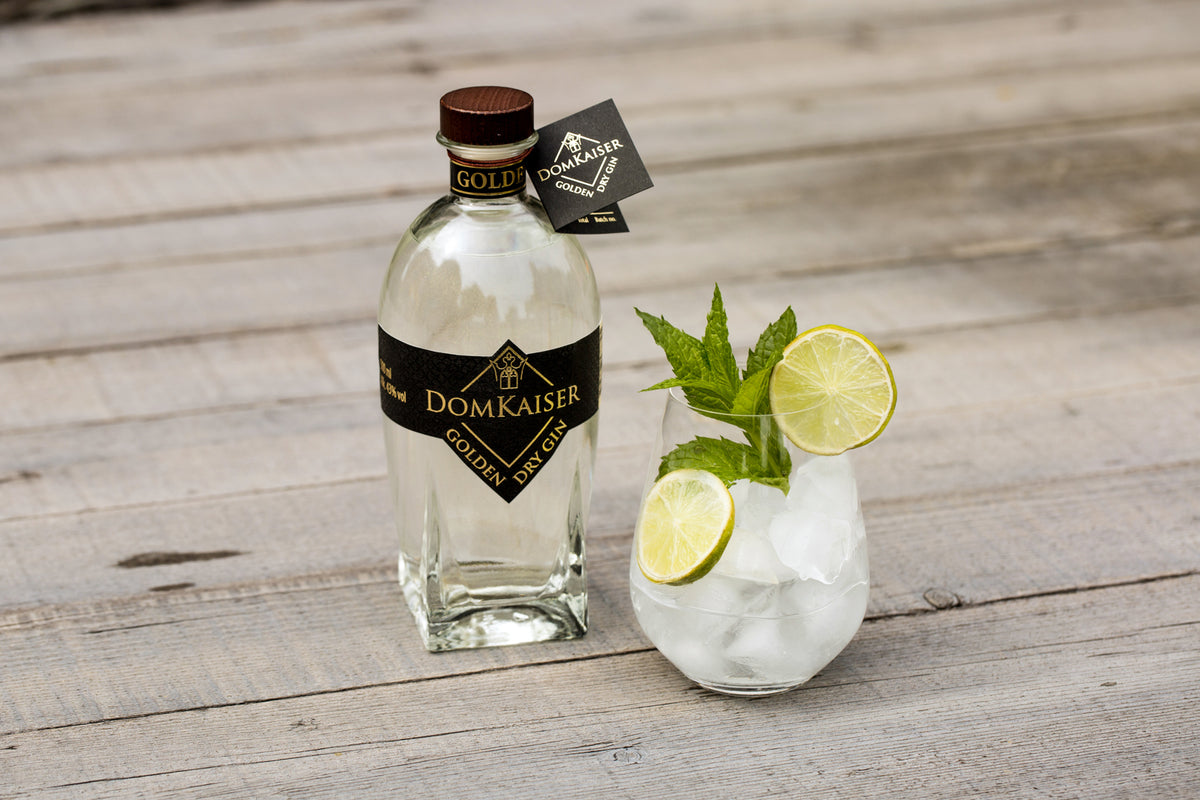 Domkaiser Golden Dry Gin mit dekoriertem Glas auf Holzdielen